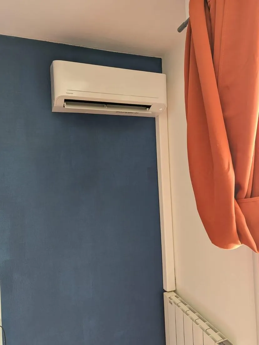 Climatisation murale réversible posée sur un mur bleu